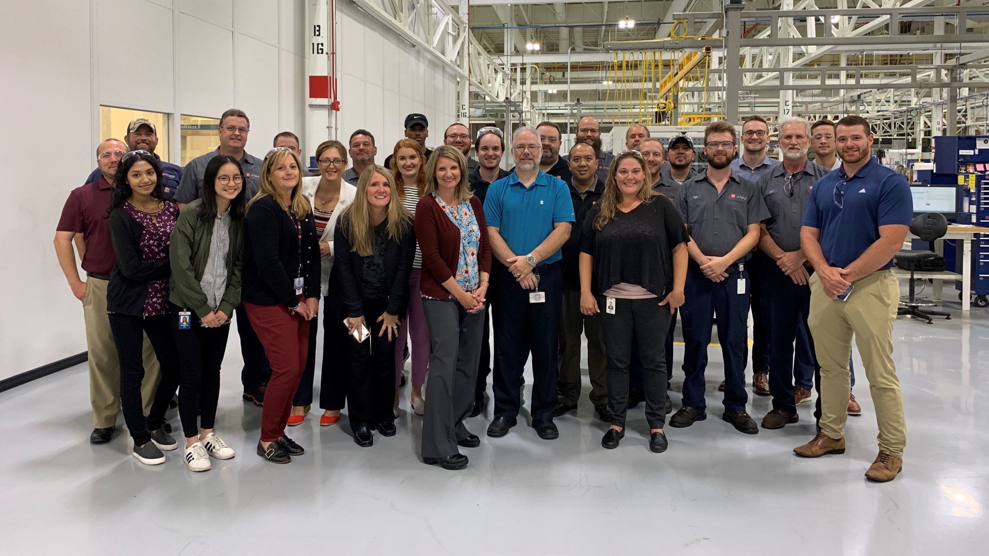 Cheryl Thompson with her team at American Axle, a large group standing together inside a manufacturing facility.