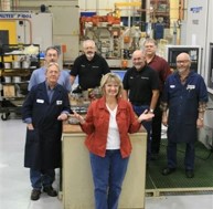Cheryl Thompson, center in a red top, with the members of her gear lab team on the shop floor.
